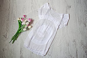 White lengthened blouse with lace, pink tulips. Fashionable concept, top view photo