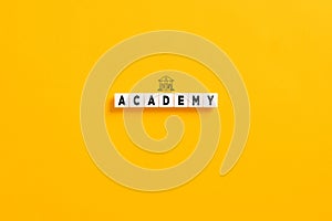 White letter blocks on yellow background with the word academy and university symbol. Higher education in college or university