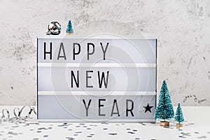 White letter lightbox with Happy New Year surrouded with christmas decorations front view