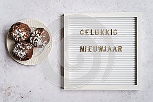 A white letterboard with Gelukkig Nieuwjaar (Dutch for Happy New Year) with oliebollen