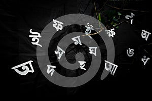 The white letters of the Bengali alphabet are Being visible in the black background.