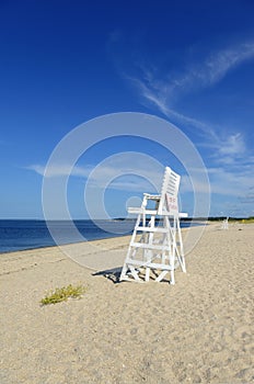 White lifeguard chair on empty sand beach with blue sky photo