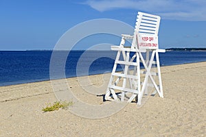 White lifeguard chair on empty sand beach with blue sky