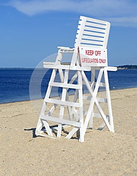 White lifeguard chair on empty sand beach with blue sky