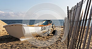 White lifeguards row boat on the sand next to a fence at Sunken Meadow State Park