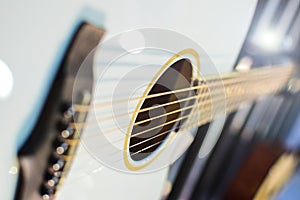 White or light blue wooden acoustic guitar close up. Lights background. Sound hole