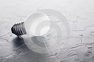 White light bulb glowing on concrete background, idea concept