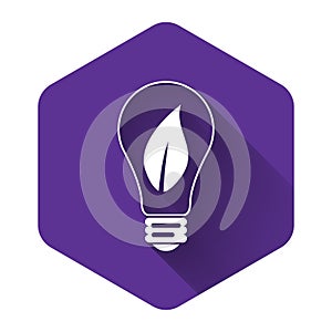 White Light bulb with leaf icon isolated with long shadow. Eco energy concept. Purple hexagon button