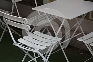 White light collapsible metal table and chairs in a summer outdoor cafe