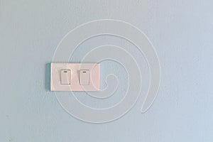 White light switch on a blue concrete wall.