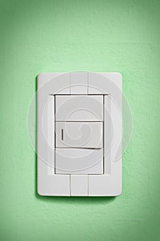 White light switch on green wall.