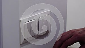 white light switch on a white wall. Turning off the light in the room