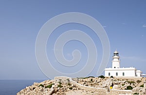 A white lighthouse on a cliff with the sea in the background on a clear summer day, Cavalleria Lighthouse, Fornells, Menorca,