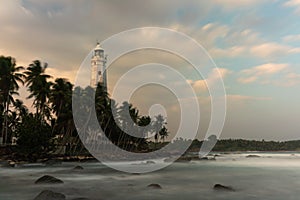 White lighthouse Dondra and tropical palm trees against the background of a fantastic sunset, Sri Lanka.