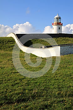 White Lighthouse on a green hill, Ireland photo
