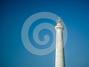 A white lighthouse set against a blue sky in the summer