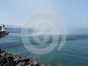 White lighthouse and water jet in Geneva european city on promenade at swiss Leman Lake landscape in Switzerland