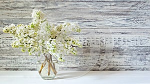 White lilac bouquet in glass vase on wooden table. Spring branches of blooming lilac festive bouquet of flowers. Long web banner