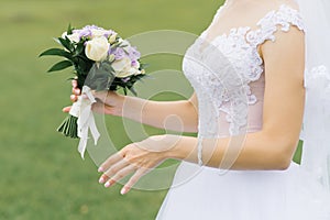 White and lilac wedding bouquet in the hands of the bride on the wedding day