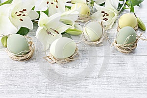 White lilies and easter eggs on wooden background photo