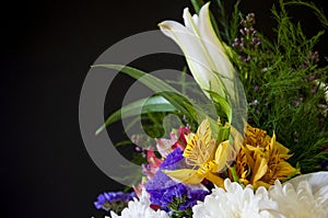 White lilyes, yellow and pink orchids, branch of lilac, chrysanthemums in the spring  tender bouquet on the background with black