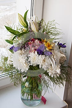 White lilyes, yellow and pink orchids, branch of lilac, chrysanthemums in the spring  tender bouquet on the background with window