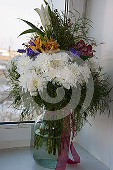 White lilyes, yellow and pink orchids, branch of lilac, chrysanthemums in the spring  tender bouquet on the background with window