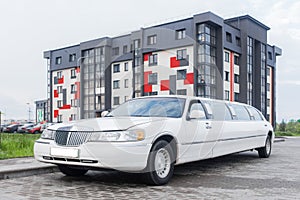 White limousine luxury long car for celebrations and celebrations against the backdrop of a modern city building