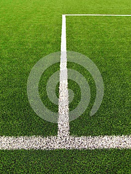 White line on artificial grass field on football playground. Detail of a cross of painted white lines in a soccer field.