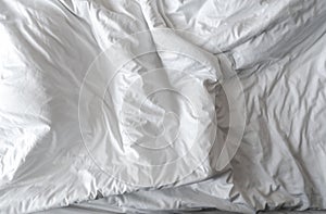 White linen blanket in hotel bedroom. Close-up detail of messy white blanket. Comfortable bed with soft white duvet. Sleep tight