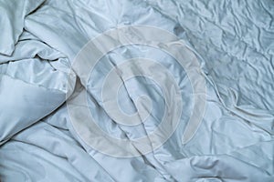 White linen blanket in hotel bedroom. Close up detail of messy white blanket after waking up in morning. Comfortable bed