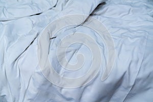 White linen blanket in hotel bedroom. Close up detail of messy white blanket after waking up in morning. Comfortable bed with soft