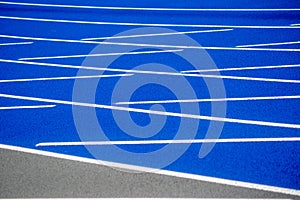 White lines on textured surface of blue running track.