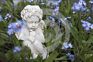 A white little angel figurine in a flower bed