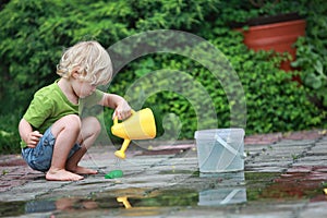 White little barefoot girl playing with water