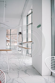 White loft restaurant interior with dining table, chairs on a sunny summer day