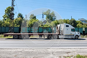 White long distance truck with a semitrailer at a freight railway station in the countryside