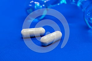 White long health capsule pills on blue background