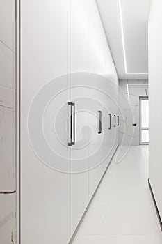 White long wardrobe from floor to ceiling. White doors with metal handles