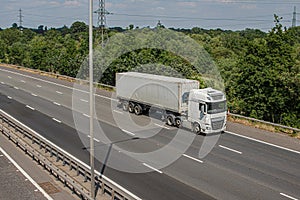 White lorry with shipping container in motion on the motorway