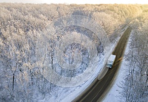 White Lorry truck on the road surrounded by winter forest. Aerial top view