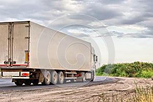 White lorry with white trailer over blue sky on the road