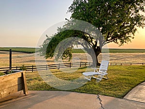 White lounge chair on a grassy knoll at sunset