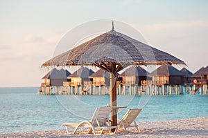 White lounge chairs on a beautiful tropical beach at Maldives