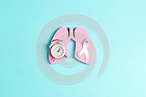 White lung cancer awareness ribbon with lung symbol and alarm clock on blue background