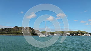 White luxurious sailboat, yacht in Caribbean ocean harbor near the green hills.