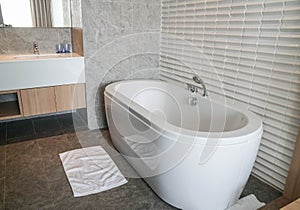 White luxury bathtub in sexy bathroom in hotel bedroom with white cotton mat for foot drying