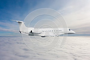 White luxury executive aircraft flies in the air above the clouds