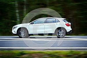 White luxury suv car goes fast through the forest