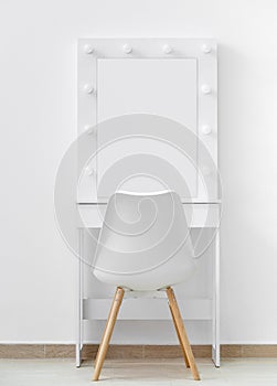 White makeup dressing table with lamps and a chair against a white wall